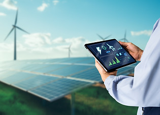 Sustainable energy management system concept.Engineer using digital tablet with wind turbi